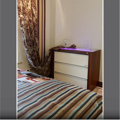 Schlafzimmer mit gestreiftem Vorhang und Teppich
